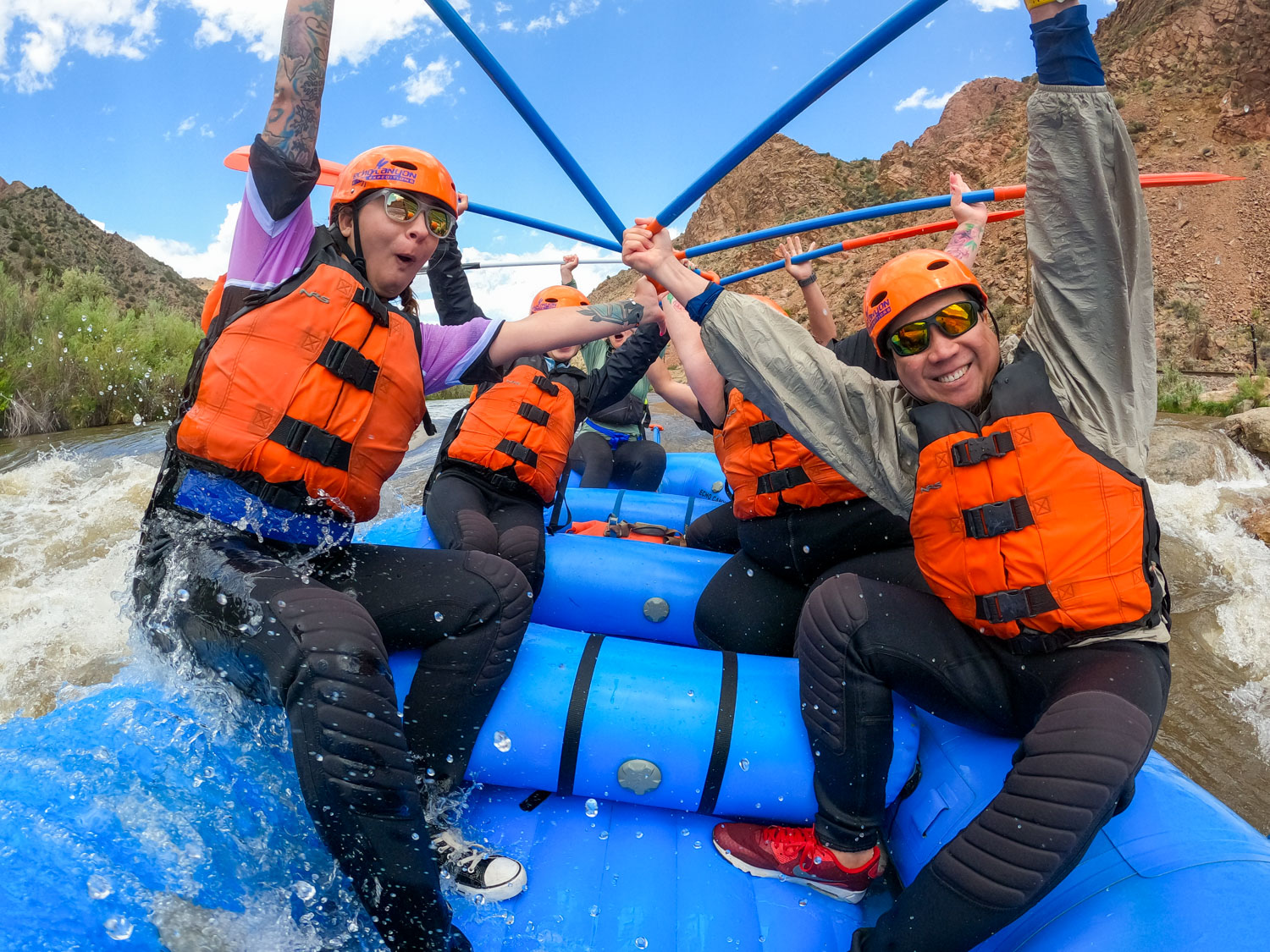 Rafters throw their paddles up in celebration after paddling a rapid